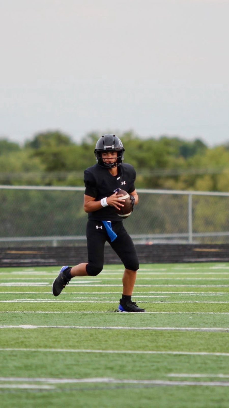 Quarterback Jack Jamison, #1, in a black uniform scrambling with the football on a green field